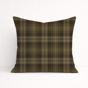 Puede incluir: Coj&iacute;n decorativo cuadrado con un estampado de cuadros en tonos verde oliva, marr&oacute;n y beige. El coj&iacute;n presenta un dise&ntilde;o tart&aacute;n cl&aacute;sico, adecuado para la decoraci&oacute;n del hogar. El coj&iacute;n tiene forma cuadrada.