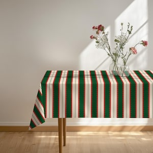 Può includere: Una tovaglia rettangolare caratterizzata da un motivo a righe verticali nei colori verde scuro, crema e rosso. Il design presenta sottili linee rosse smerlate che bordano le strisce verdi, creando un motivo strutturato e ripetitivo.
