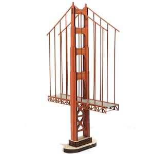 May include: A wooden model of the Golden Gate Bridge, painted red with a brown base. The bridge is a popular landmark in San Francisco, California.