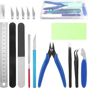 May include: A craft tool kit with various tools, including a ruler, cutting blades, files, tweezers, and a wire cutter. The tools are in a clear plastic container and arranged on a white surface. The ruler is marked with inches.