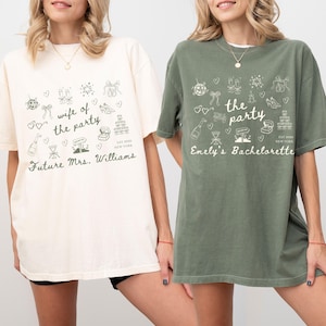 May include: Two oversized t-shirts, one cream and one olive green, with matching graphics. The cream shirt says "wife of the party" and "Future Mrs. Williams." The green shirt says "the party" and "Emely's Bachelorette." Both shirts have wedding-themed doodles.