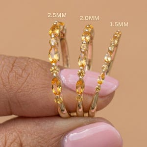Peut inclure: Trois bagues en or ornées de pierres précieuses jaunes sont présentées. Les bagues sont étiquetées 2,5 mm, 2,0 mm et 1,5 mm. Les pierres précieuses sont ovales et rondes, serties dans une monture en or.
