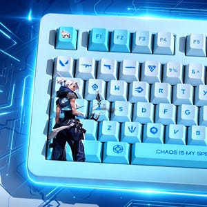 Pode incluir: Um teclado mecânico azul claro com teclas brancas. As teclas apresentam vários símbolos e ícones, incluindo uma ilustração de personagem. O texto "CHAOS IS MY SPE" é visível no teclado.