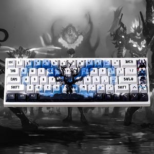 Könnte beinhalten: Weiße mechanische Tastatur mit individuellen Tastenkappen. Die Tastenkappen zeigen ein blaues und schwarzes Baum- und Wolkenmuster. Die Tastatur hat einen weißen Rahmen und verschiedene Funktionstasten.