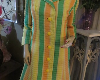 May include: A vintage striped dress with a yellow, orange, and green color scheme. The dress has a button-up front and a flared skirt. The buttons are yellow with a flower design.
