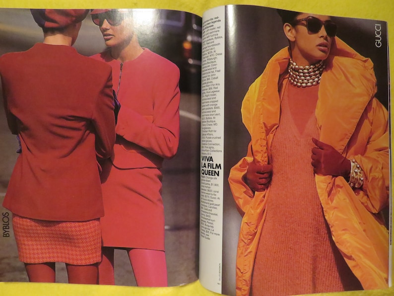 K&ouml;nnte beinhalten: Zwei Frauen in roten und orangen Jacken und Sonnenbrillen. Die Frau links tr&auml;gt einen roten karierten Rock und die Frau rechts tr&auml;gt eine lange orange Jacke mit einem wei&szlig;en Rollkragen darunter. Der Text "VIVA LA FILM QUEEN" ist im Hintergrund sichtbar.