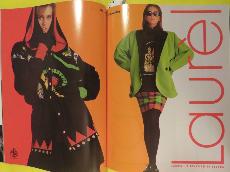 K&ouml;nnte beinhalten: Zwei Frauen pr&auml;sentieren Kleidung. Die Frau links tr&auml;gt eine schwarze und gr&uuml;ne Jacke mit rotem und wei&szlig;em Besatz. Die Frau rechts tr&auml;gt eine gr&uuml;ne Jacke &uuml;ber einem schwarzen Shirt und einem rot-schwarzen karierten Rock. Der Text "LAUREL - A DIVISION OF ESCADA" befindet sich am unteren Rand der Seite.