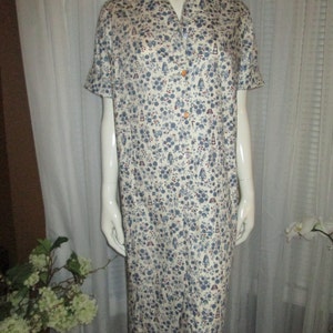 Könnte beinhalten: Ein weißes Kleid mit blauem und rotem Blumendruck. Das Kleid hat einen Kragen und kurze Ärmel.