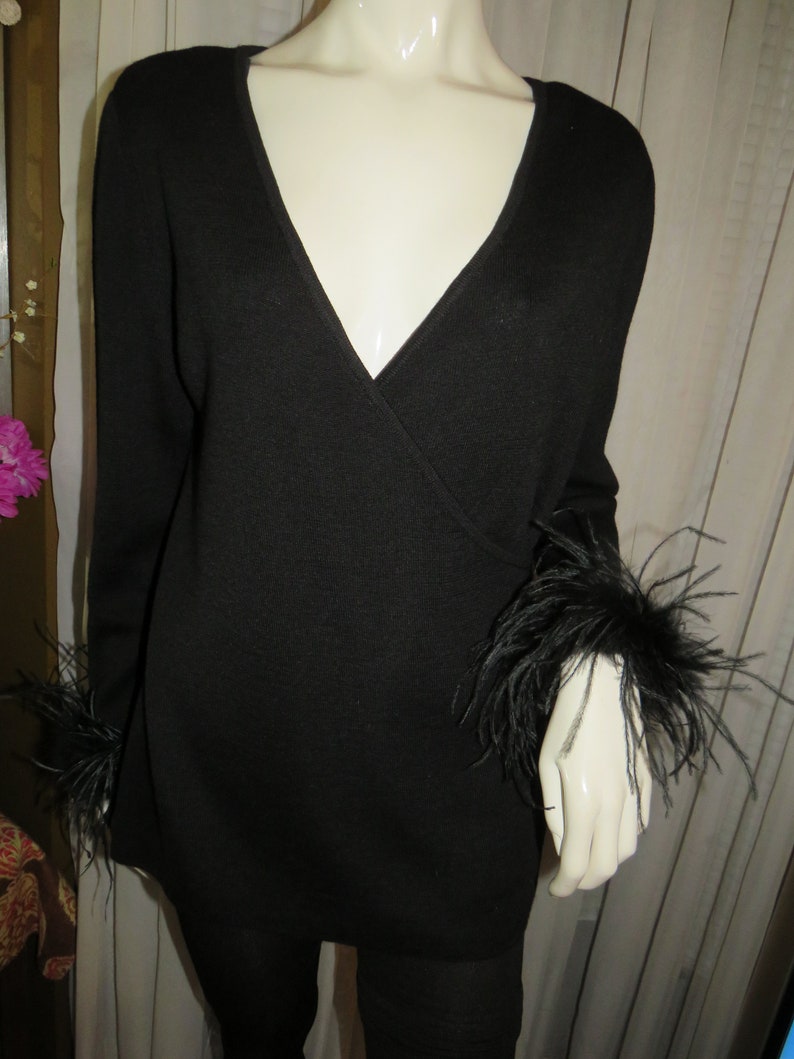 May include: Black long-sleeved sweater with a V-neck and feather trim on the cuffs.