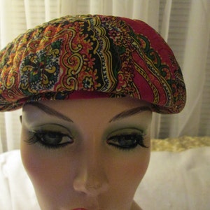 Può includere: Un berretto a tinta unita rosso, giallo e blu con una texture trapuntata.