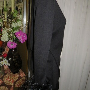 May include: Black long-sleeved sweater with feather trim on the cuffs.
