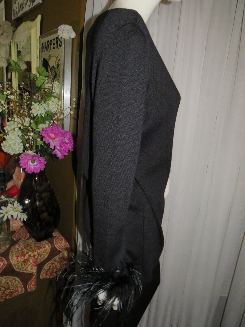 May include: Black long-sleeved sweater with feather trim on the cuffs.