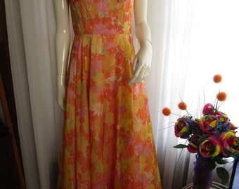 May include: A long, flowing dress with a floral print in shades of orange, yellow, and pink. The dress has a scoop neckline and ruffled sleeves.