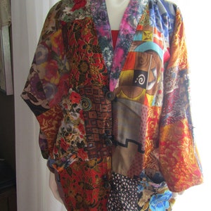 Può includere: Una giacca colorata in patchwork con una varietà di motivi floreali e geometrici. La giacca ha un collo a V e una chiusura con bottone. È realizzata in un tessuto leggero e ha una vestibilità rilassata.