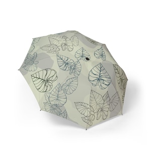 May include: An open umbrella with a light beige background and a repeating pattern of stylized leaves in dark blue and black. The leaves are in various sizes and orientations, creating a natural, botanical theme.