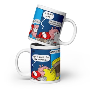 May include: A white ceramic mug featuring a colorful cartoon comic strip. The graphic depicts a red heart character and a pink brain character with speech bubbles containing the text: "Ugh, I don't feel like working...", "It didn't work.", and "Oh right, we just don't like working."