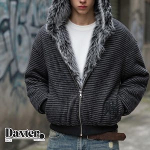 May include: A dark gray zip-up hoodie featuring thin horizontal white stripes and a thick, plush faux fur trim along the hood and front opening. The jacket has a silver-tone metal zipper, a black ribbed hem, and a subtle embroidered logo detail.