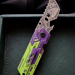 May include: A folding pocket knife with a purple and lime green handle featuring mechanical-style detailing and the text NO TOUCH. The metal blade displays an intricate laser-engraved graphic of a shark amidst stylized waves and a bottle opener cutout.