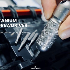 Op de afbeelding: Een zilverkleurige titanium schroevendraaier met een getextureerd handvat met een cirkelvormig golfpatroon. Het gereedschap bevat meerdere verwisselbare bits en toont de tekst TITANIUM SCREWDRIVER, Compact. Durable. Ready for Anything. en WANERSEN.
