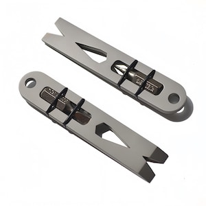 Könnte beinhalten: Zwei silberfarbene Metall-Multitools mit flachem, länglichem Design. Jedes Werkzeug verfügt über ein V-förmiges Hebelende, ein kreisförmiges Loch am anderen Ende und einen mittigen Ausschnitt, der einen Metall-Schraubendreherbit mit zwei schwarzen Gummiringen hält.