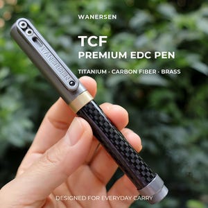 May include: A Wanersen TCF Premium EDC Pen featuring a grey titanium clip with the brand name, a brass accent ring, and a black carbon fibre barrel. The text on the pen reads WANERSEN TCF PREMIUM EDC PEN TITANIUM CARBON FIBRE BRASS.