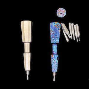 May include: Two precision screwdrivers with faceted handles. One is matte silver, the other features a blue, orange, and silver patterned finish. A circular cap and five interchangeable metal screwdriver bits are arranged nearby on a black background.