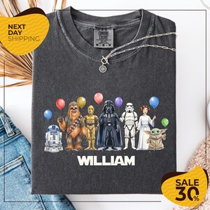 A t-shirt with a graphic design featuring characters from the Star Wars franchise, including Chewbacca, Darth Vader, Stormtrooper, and Yoda, along with colorful balloons. The text "William" is displayed below the characters, and there are two yellow sale signs indicating a 30% discount on the t-shirt.