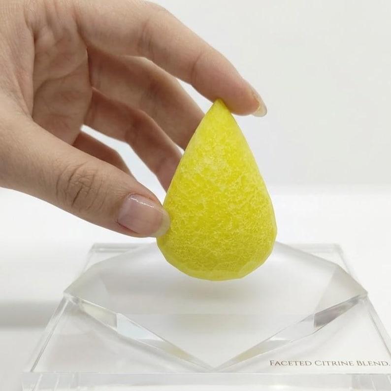 Natural yellow sapphire rough gem pear shaped with polished surface and golden yellow tone displayed on soft fabric, raw Jupiter Pukhraj crystal ideal for astrology, jewelry making, meditation, and prosperity rituals.
