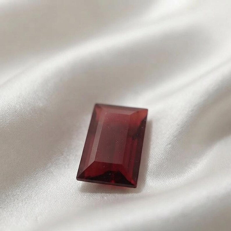Deep red ruby baguette cut gemstone with step cut faceting and polished finish, ideal for engagement ring accents, wedding jewelry, and luxury bracelet settings.