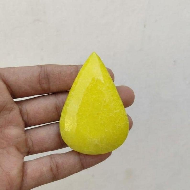 Natural loose yellow sapphire stone in pear shape featuring smooth surface and warm golden tone, ideal for pendants and ring settings.
