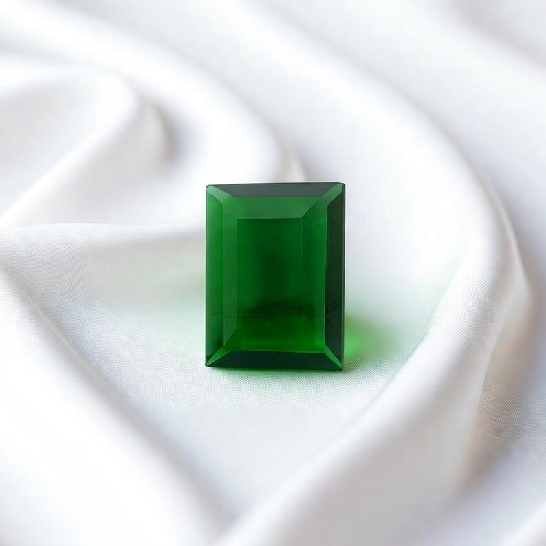 High quality green emerald rectangle cut gemstone with step cut facets and natural inclusions, perfect for jewelry designers, May birthstone gift and collector grade precious gem collections.