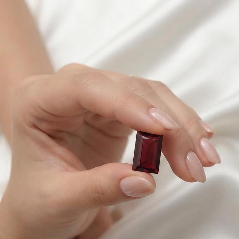 Natural red ruby baguette cut gemstone displayed on soft fabric background, showcasing deep red color and elegant rectangular faceting, ideal loose ruby stone for engagement rings, bracelet settings, and July birthstone jewelry.