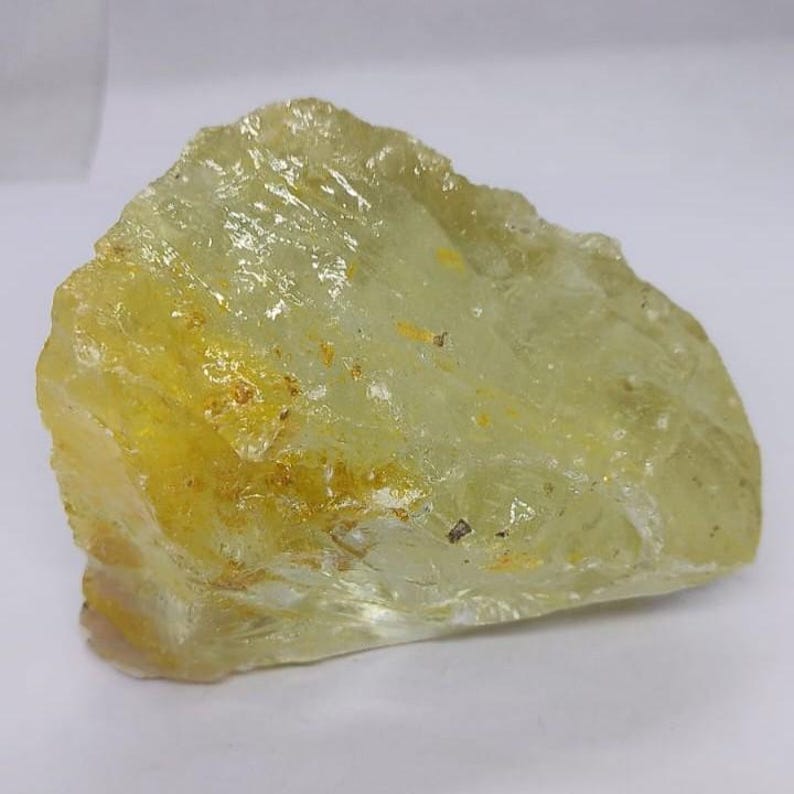 Natural lemon quartz rough crystal stone with organic shape and translucent yellow glow, perfect for spiritual altar decor and gemstone crafting projects.