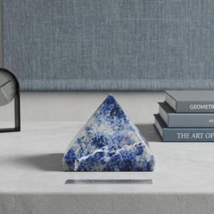 Handmade natural sodalite pyramid crystal used for throat chakra healing, Reiki therapy and mindfulness practices in sacred spaces.