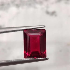 Close up of deep crimson ruby cabochon gemstone showing glossy finish and rich red hue, perfect July birthstone for fine jewelry making