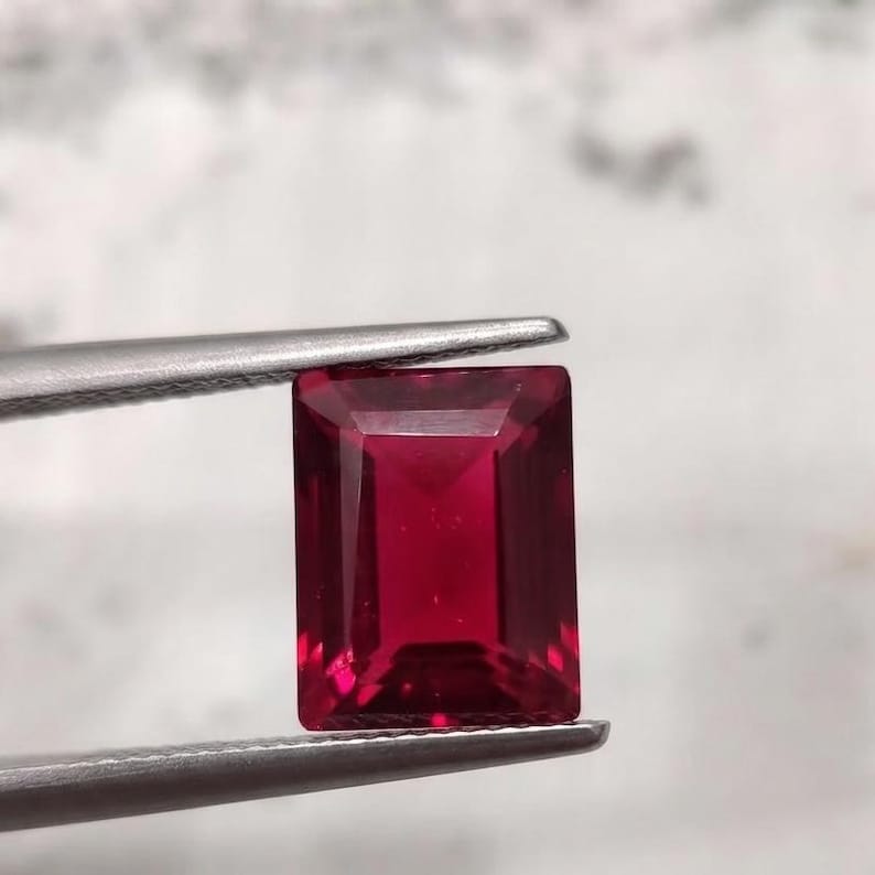 Close up of deep crimson ruby cabochon gemstone showing glossy finish and rich red hue, perfect July birthstone for fine jewelry making