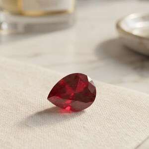 Close up of pear shaped natural ruby loose gemstone showing deep red saturation and sparkling facets, perfect July birthstone for pendant or ring making