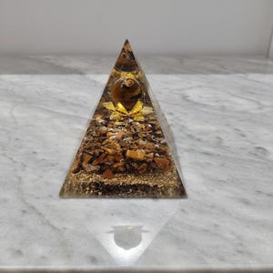 Close-up of tiger eye chakra pyramid showcasing natural golden chatoyancy, used for Reiki healing and solar plexus chakra balancing.