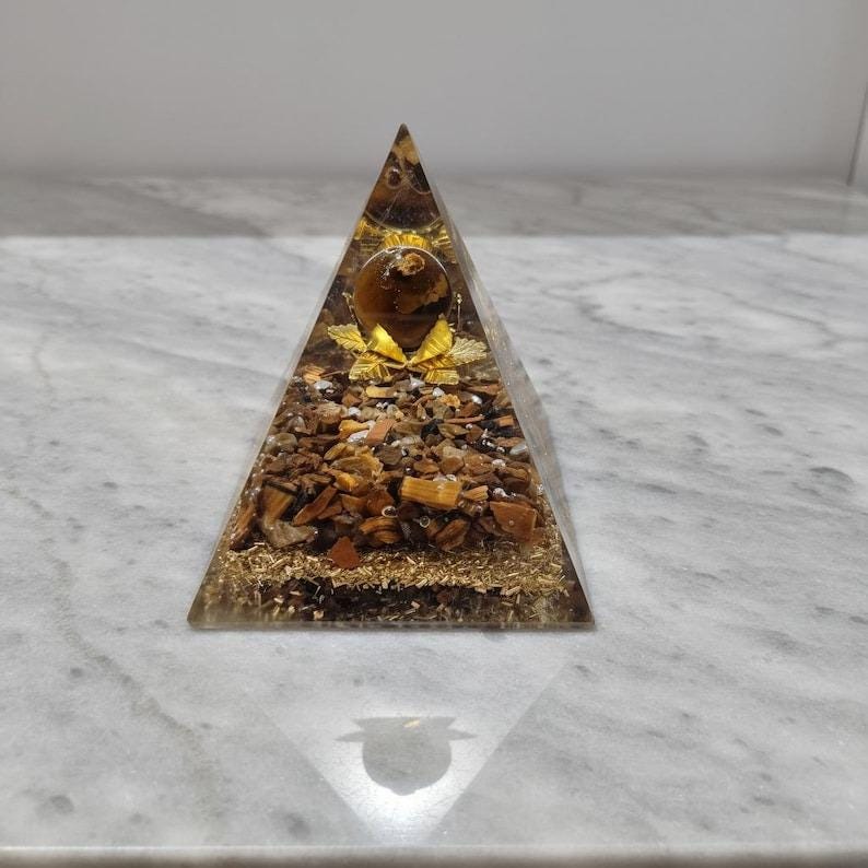 Close-up of tiger eye chakra pyramid showcasing natural golden chatoyancy, used for Reiki healing and solar plexus chakra balancing.