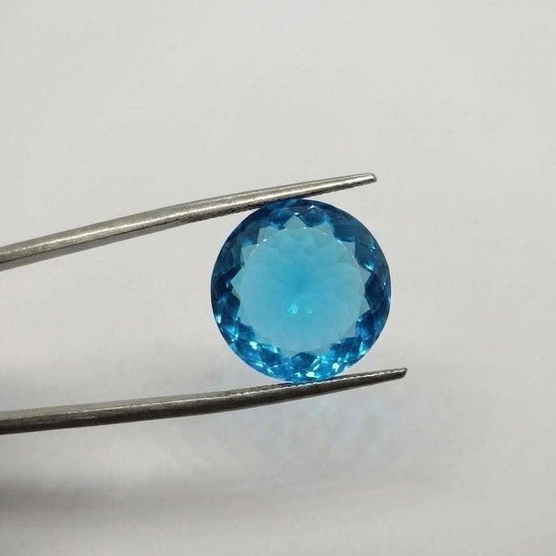 Round cut blue topaz gemstone with vibrant Swiss blue color and polished finish, perfect for engagement rings and December birthstone jewelry.