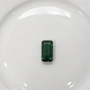 Deep green natural emerald gemstone in emerald cut shape shown as loose stone for ring setting, fine jewelry design, luxury engagement ring centerpiece and May birthstone crystal gift.