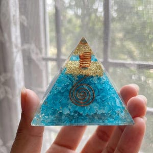 Amazonite orgone energy pyramid with copper coil, used for Reiki healing sessions, throat chakra alignment, manifestation rituals, and desk decor near electronics.