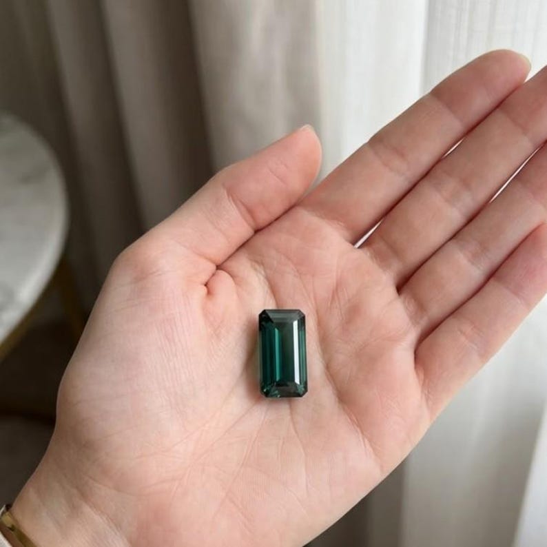 Natural green emerald stone in classic emerald cut shape displayed as a loose gemstone, featuring a rectangular faceted design with deep green color, ideal for engagement rings, fine jewelry making, custom ring settings and May birthstone gifts.