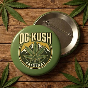 May include: A green button with the text "OG KUSH ORIGINAL" in a white and yellow font. The button features a cannabis leaf design with mountains in the background. The button is round and has a metal pin back.