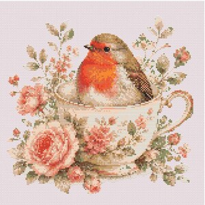 Puede incluir: Diseño de punto de cruz de un petirrojo en una taza floral. El ave tiene un pecho naranja brillante y plumas marrones. La taza está decorada con rosas rosas y follaje verde, sobre un fondo rosa pálido.
