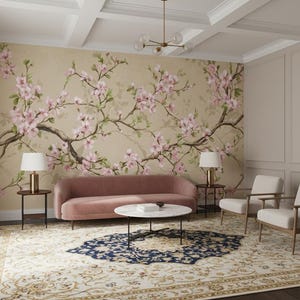 Könnte beinhalten: Ein Wohnzimmer mit einer floralen Tapete mit rosa Blüten und Zweigen. Der Raum umfasst ein rosa Sofa, zwei Sessel, einen Couchtisch und einen gemusterten Teppich. Zwei Lampen stehen auf Beistelltischen.