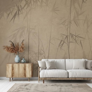 May include: A living room with bamboo-patterned wallpaper in shades of tan. A white sofa with light cushions is positioned against the wall. A wooden cabinet with vases and dried plants is on the left. A beige rug is on the floor.
