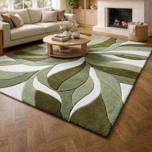 May include: A rectangular area rug featuring a large-scale, abstract leaf pattern in varying shades of olive green, sage green, and white. The design consists of thick, curved, overlapping shapes that create a textured, layered appearance across the surface.