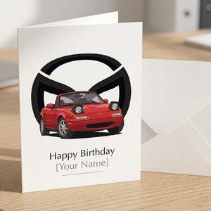 May include: A white greeting card featuring a red convertible sports car with pop-up headlights positioned in front of a large black circular logo. The text Happy Birthday [Your Name] is printed in black below the car illustration.