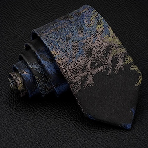 Peut inclure: Une cravate avec une base noire ornée d'un motif abstrait et texturé dans des tons de bleu, d'or et de bronze. Le design ressemble à un motif dense, organique ou forestier qui se déploie sur le tissu, lequel est enroulé en spirale.